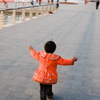 Es ist ein unscharfes, aber mein Lieblingsphoto aus der Zeit in China. Ein Kind, vielleicht ein M?dchen, hat eine leuchtend rote Jacke an, und es l?uft, die Arme weit ausgebreitet, an einem See entlang.